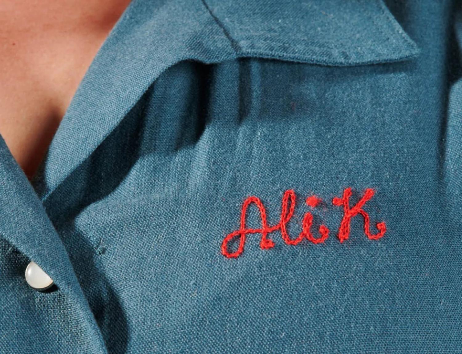 翻领衬衫上的定制刺绣名牌特写，上面写着“Ali K”。